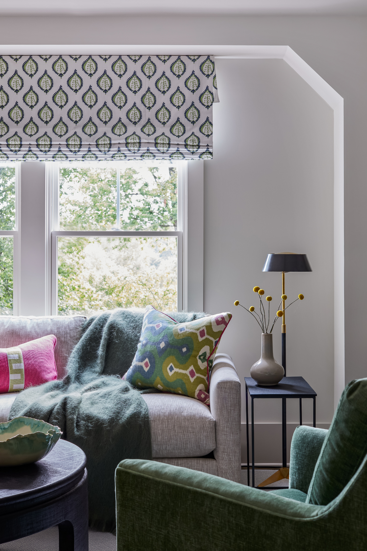 Cozy living corner with patterned drapery, pink pillow, and gold accents
